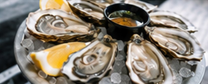 Oysters on ice with lemon and a pot of dressing.